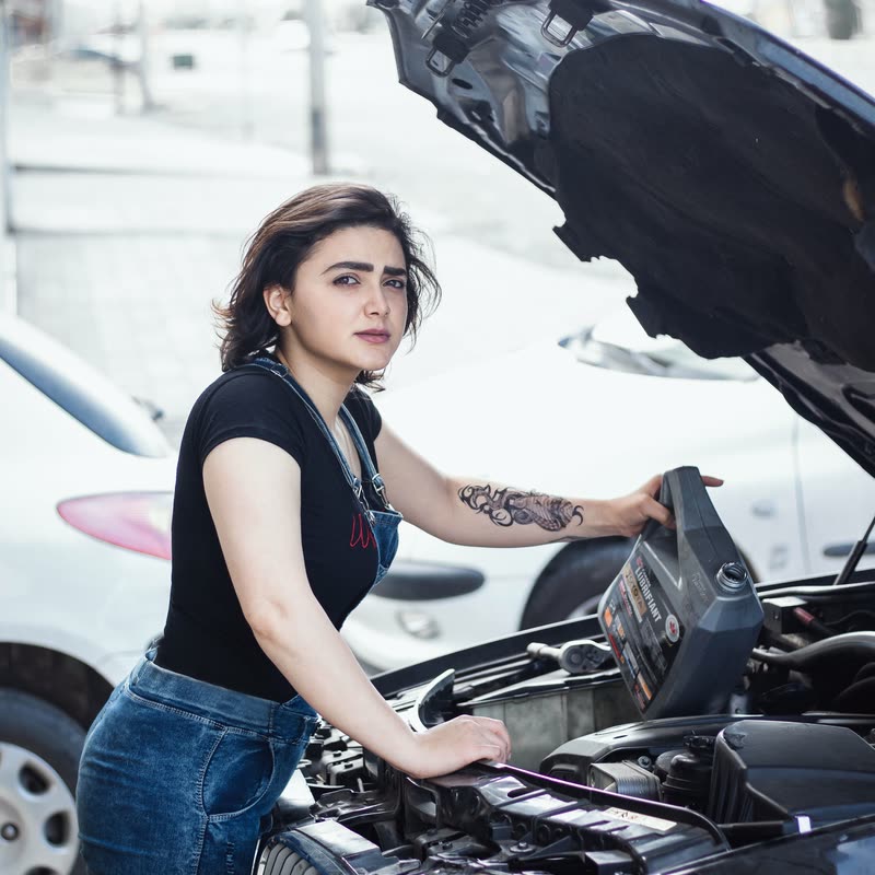 Nina Exempel lutar sig över ett öppet motorrum.